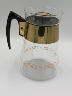 Vintage Pyrex Glass Coffee Carafe – Gold Scroll Pattern – Mid-Century Modern – 6 Cup: Vintage Corning Pyrex heat-proof glass coffee carafe, dating to the 1950s–1960s, featuring an elegant gold scroll/starburst pattern.The carafe has a clear glass body with a wide gold band at the top