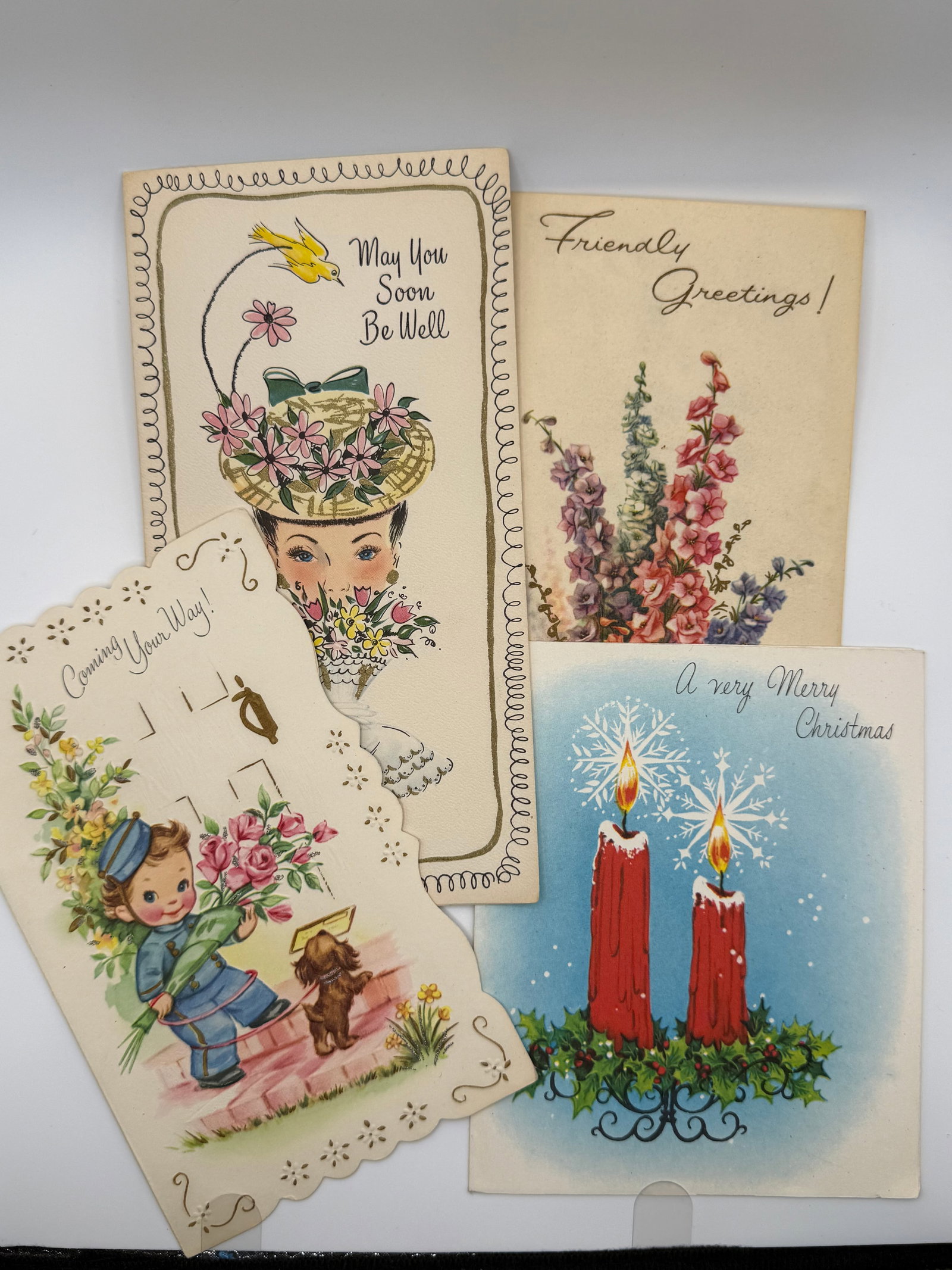 4 Vintage Greeting Cards – Get Well, Friendly Greetings, Christmas Candles & Die-Cut Boy with: Group of four vintage greeting cards featuring a mix of sentimental and holiday themes in classic mid-20th century style.Included:“May You Soon Be Well” get well card with woman in floral hat