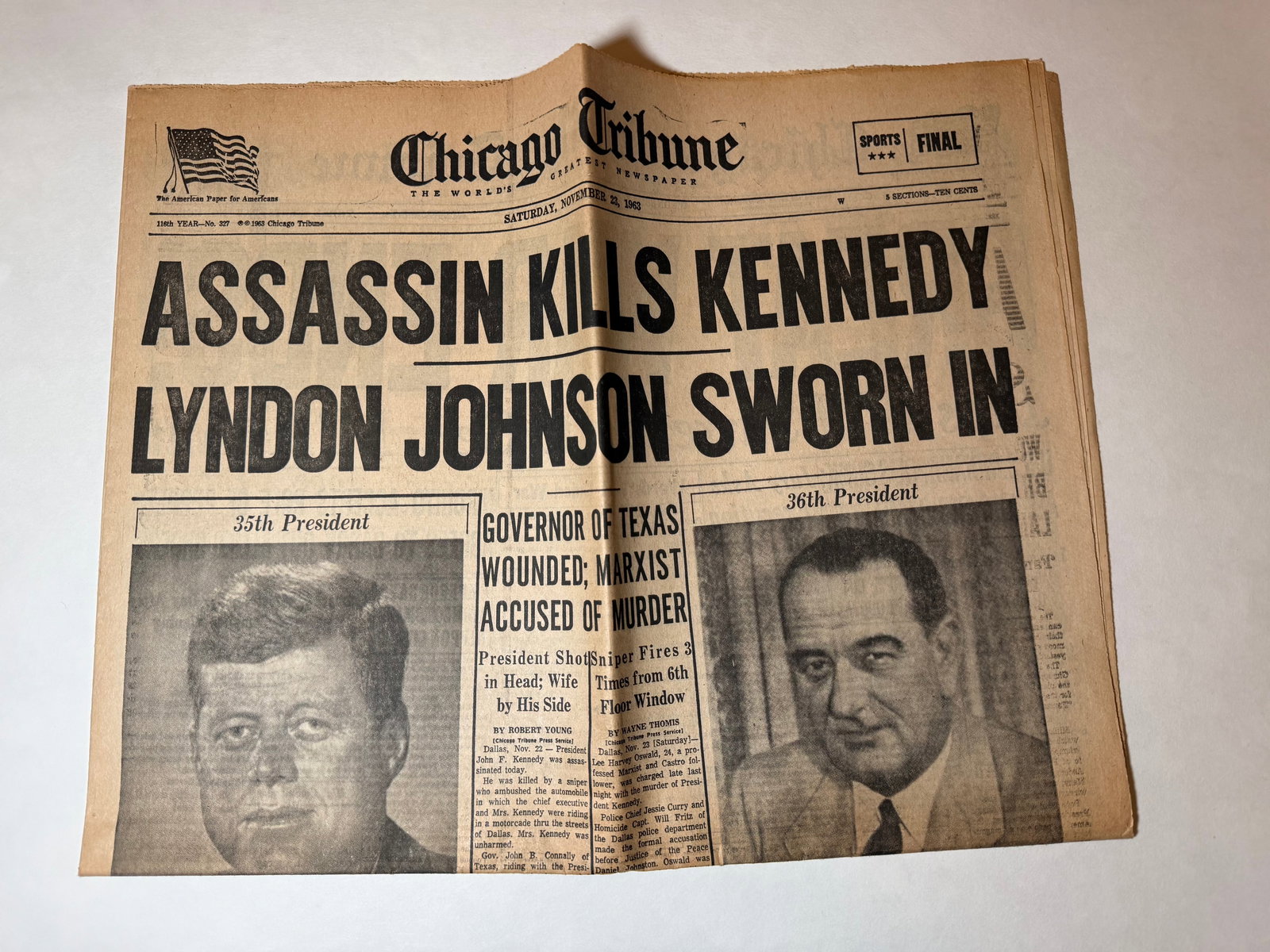 1963 Chicago Tribune JFK Assassination Newspaper Assassin Kills Kennedy Johnson Sworn In: Original Chicago Tribune front page dated November 23, 1963, featuring bold historic headline:“ASSASSIN KILLS KENNEDY – LYNDON JOHNSON SWORN IN”Covers the immediate aftermath of President Jo