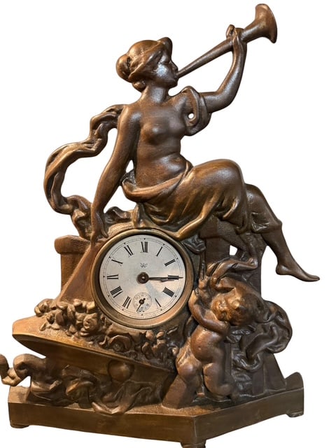 Golden Novelty Mfg. Co. Chicago Figural Metal Mantel Clock, Maiden with Trumpet: Early 20th-century figural mantel clock by Golden Novelty Manufacturing Co., Chicago, featuring a classical maiden seated atop a pedestal sounding a trumpet, accompanied by a cherub amid flowing folia