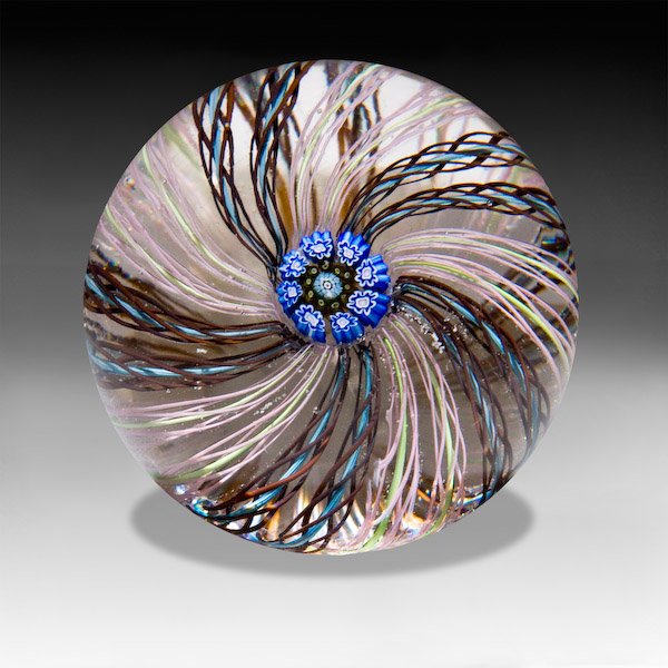 Perthshire: Medium swirl weight with a blue complex center cane and multicolored spiral threads extending outward and wrapped around to the bottom. The weight has a clear ground and a flat, polished base. Unsigne