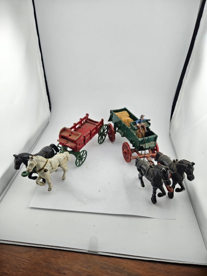 A Pair of Different Cast Iron Wagons.: A Pair of Different Cast Iron Wagons. The One on the Right has Black Horses and Bales of Hay in the Cart. The One on the Left Has a Black and White Horse, and No Driver. They Both Have All Their Wheel