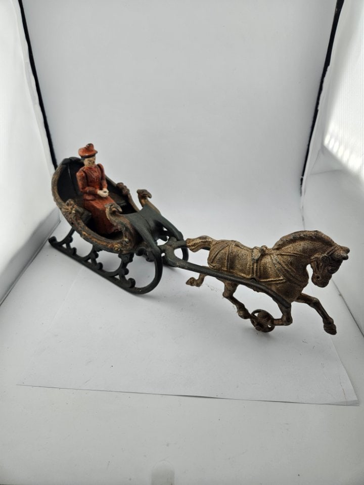 Antique Cast Iron Horse Driven Sleigh with Passenger: Antique Cast Iron Horse Driven Sleigh with Passenger. 14" long. The lady is in a red dress as she goes on a journey in her sleigh.