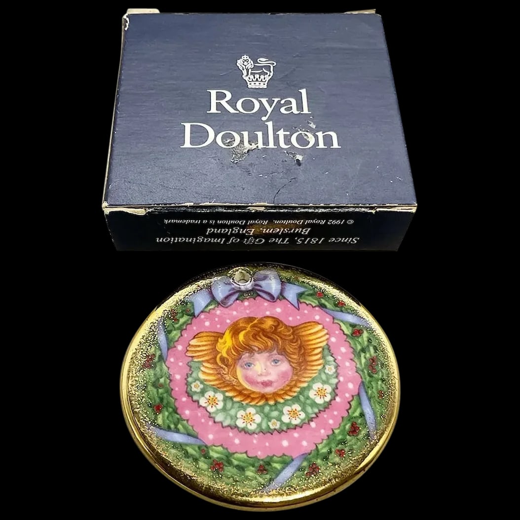 Christmas Ornament: Royal Doulton Joy of Christmas 1992 Ornament Gold Trim by Carol Lawson a renowned English Artist. It features an Angel in the center of a wreath that is trimmed in gold. The back is also a wreath