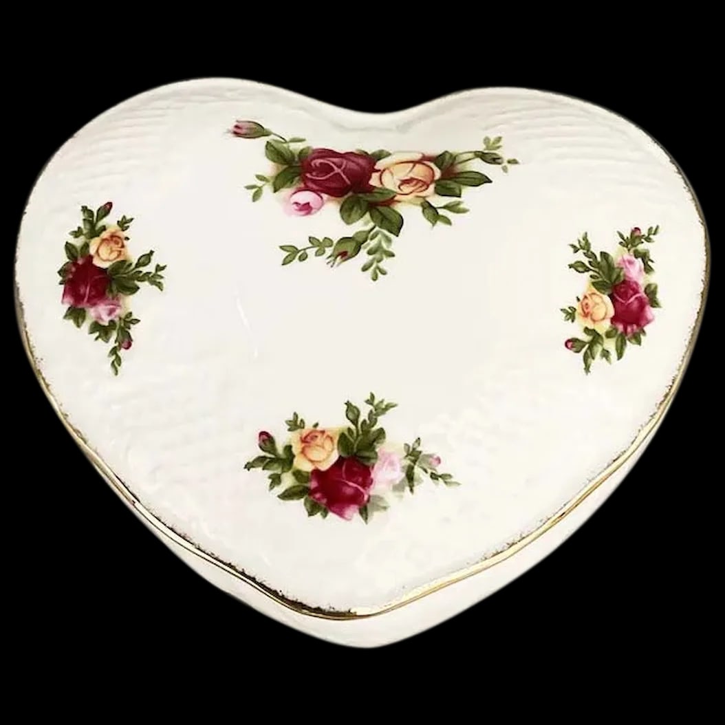 Trinket Box: Royal Albert Heart Shaped Trinket Box is designed with pink, yellow and peach-colored roses, with a raised lace relief and gold trim. It is made from fine bone china and signed Old Country Roses,