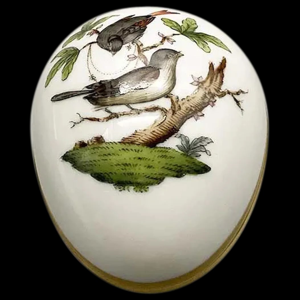 Egg Shaped Trinket Box: Herend Rothschild Egg the dainty detail of this Rothschild egg is symbolic of spring and rebirth. A mama and daddy bird are perched on a branch dotted with tiny pink buds. They are hovering over