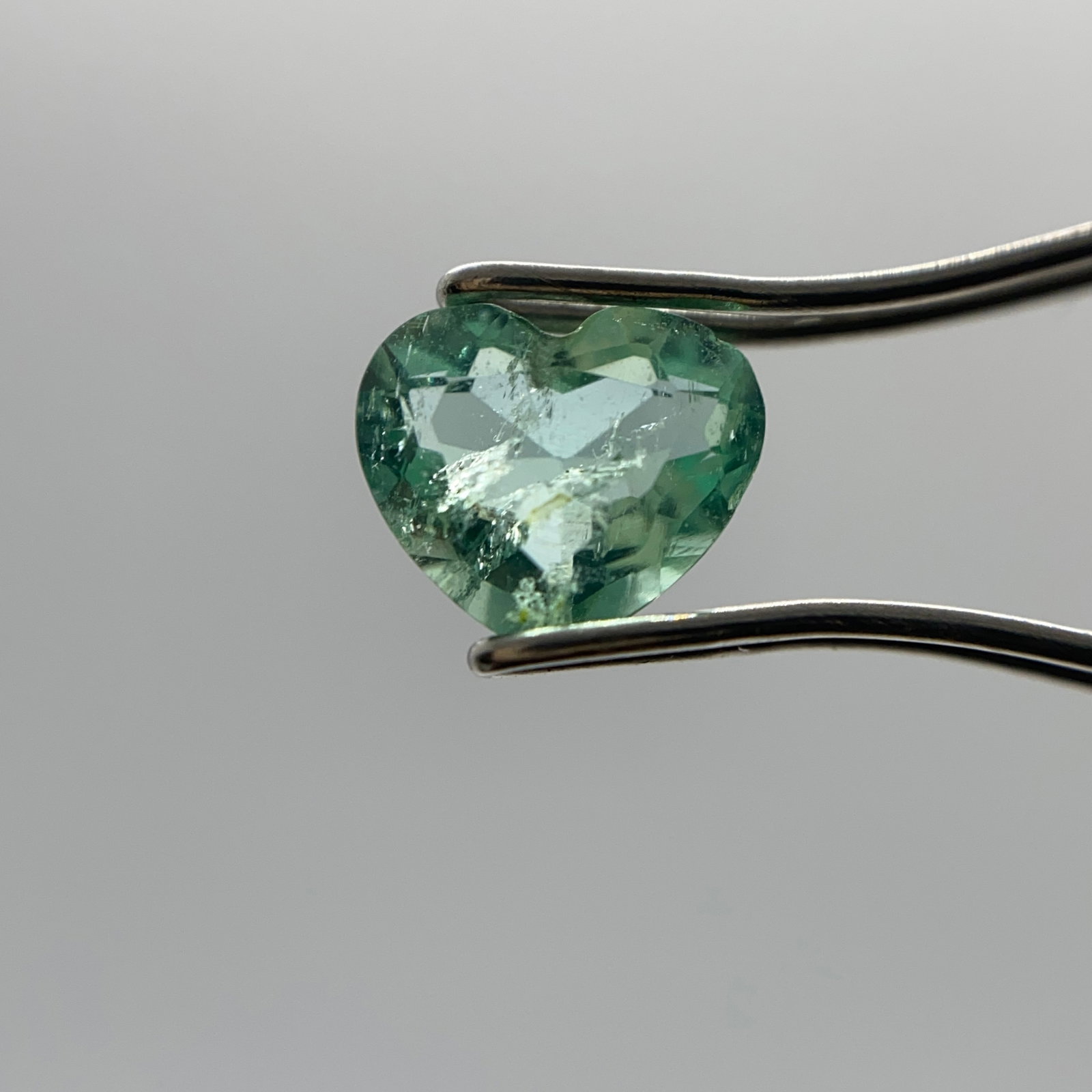 Rare 0.66ct Natural Colombian Heart Emerald: A fully Colombian emerald cut into a brilliant heart shape, displaying the highly prized vivid green saturation. Vivid green Colombian emeralds cut into brilliant heart shapes are exceptionally rare a