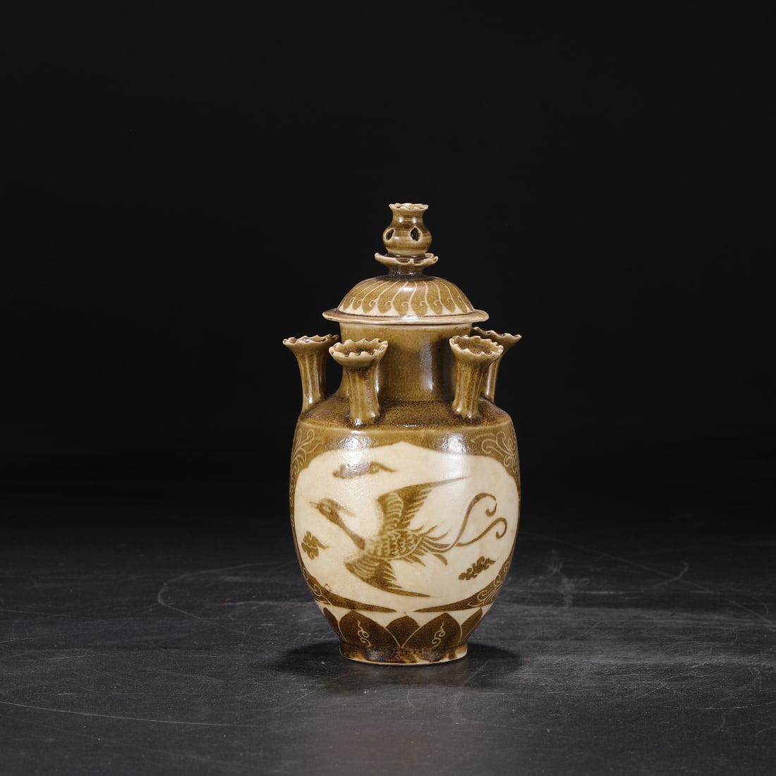 A five-tube bottle with a phoenix pattern carved in brown color from the Ding kiln in the Song: The brown color carved phoenix pattern five-tube bottle of the Song Dynasty Ding kiln Size:H:25cm Calibre:4cm Belly diameter:10.5cm (The Dimensions Of All Batches Are Manually Measured.If You Need