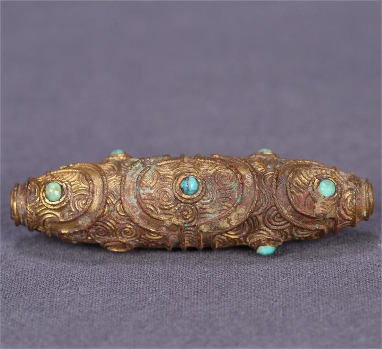 A copper-gilt turquoise Dzi from the Tang Dynasty: The copper gilt of the Tang Dynasty is inlaid with turquoise dzi Size:5.8x1.7cm W:0.0242kg (The Dimensions Of All Batches Are Manually Measured.If You Need More Detailed Information, Please Contact Ou
