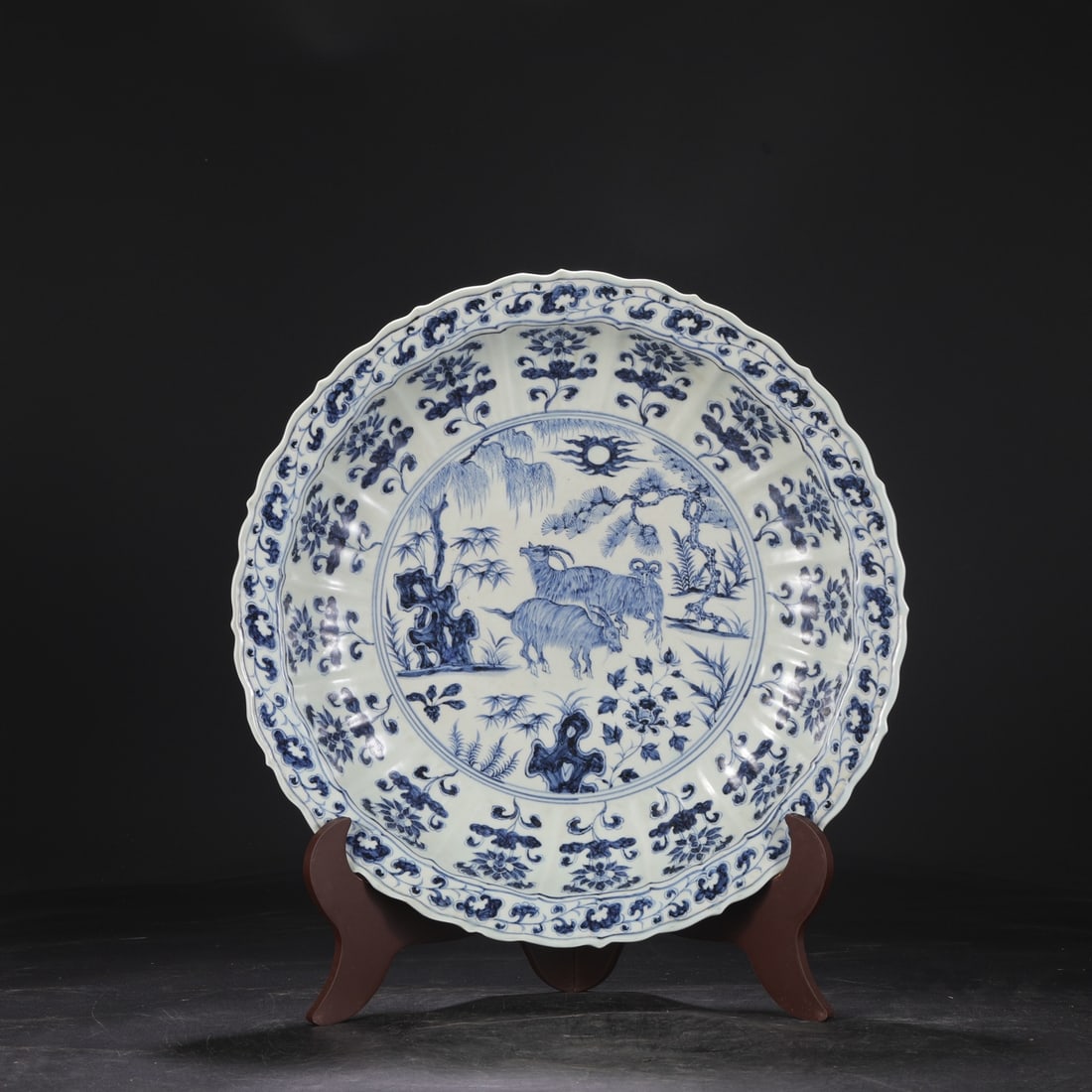 A large plate with a large rim made in the Ming Dynasty Hongwu period, featuring bamboo, stone, goat: A large plate with a large rim with a blue and white bamboo, stone, goat floral design, and melon-ridged rim, made during the Hongwu period of the Ming Dynasty Size: H:7cm D:43.5 cm Size: H:7cm D:43.5