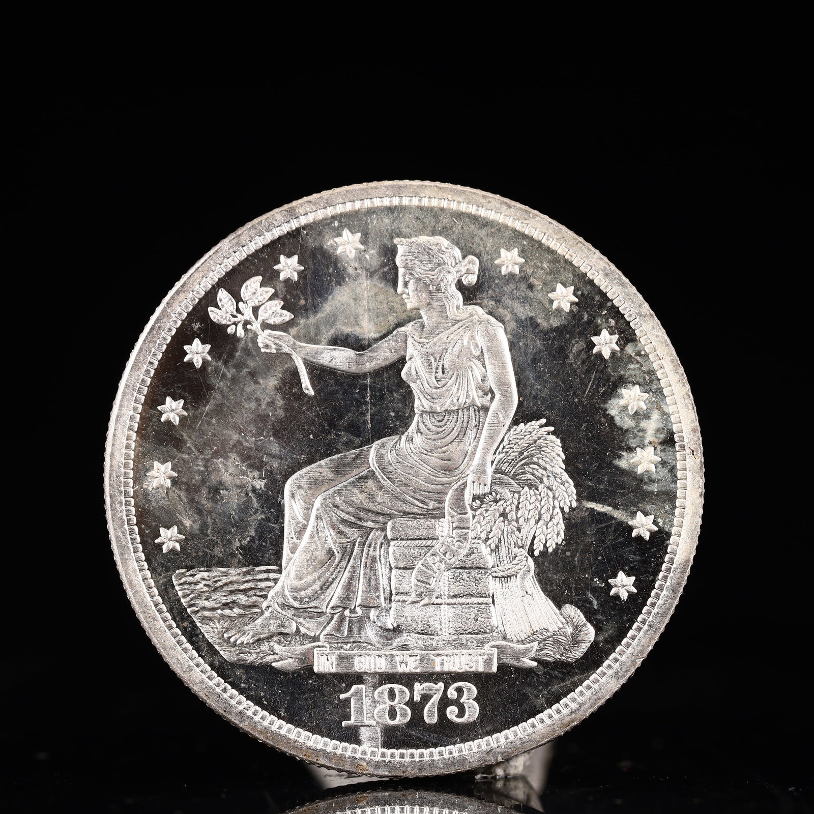 USA Trade Dollar 1873 Coin: American coin. Obverse: Liberty seated on a pedestal facing the sea to the left holding olive branches surrounded by 13 stars. IN GOD WE TRUST / LIBERTY / 1873. Reverse: An eagle holding branches with