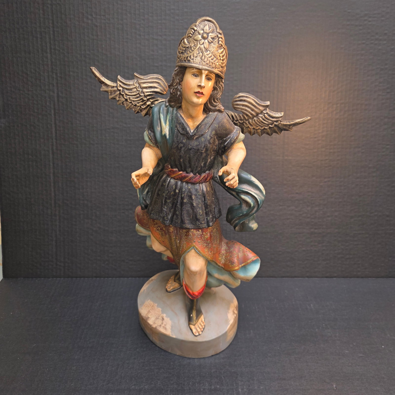 Large Peruvian Wooden Santo Statue of the Archangel Michael: Wonderful wood statue of Archangel Michael with pressed tin wings and crown. Handpainted with vibrant colors and gold paint. This is a Peruvian-features intricate polychrome paint and gilding.