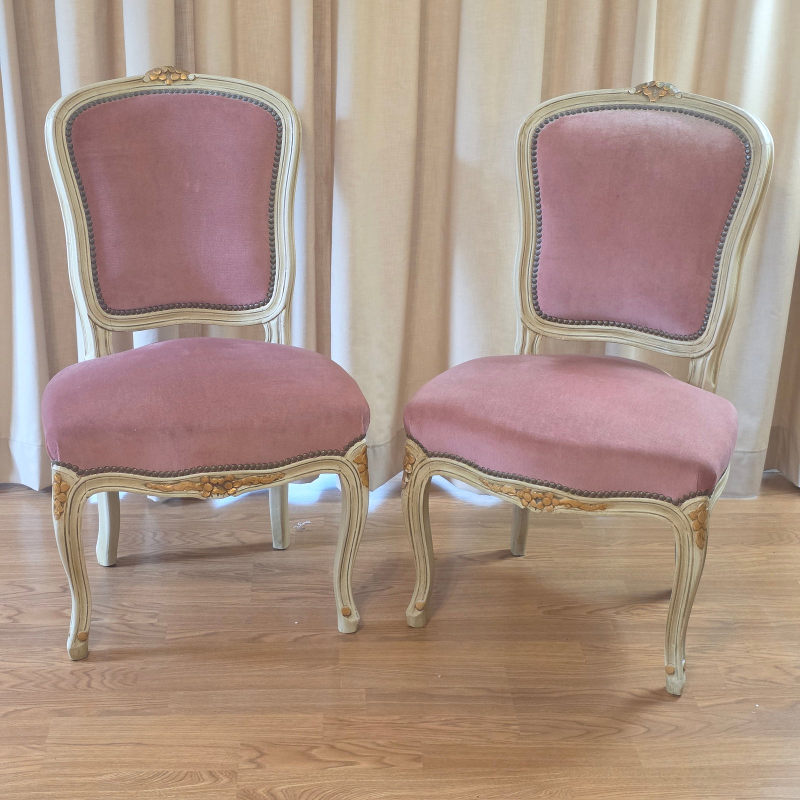 French Louis XV Style Dining Chairs with Pink Velvet Upholstery: A fine pair of late 19th to mid-20th-century French Provincial Louis XV style dining or salon side chairs. Each chair is skillfully crafted with an open-back wooden frame featuring a molded,