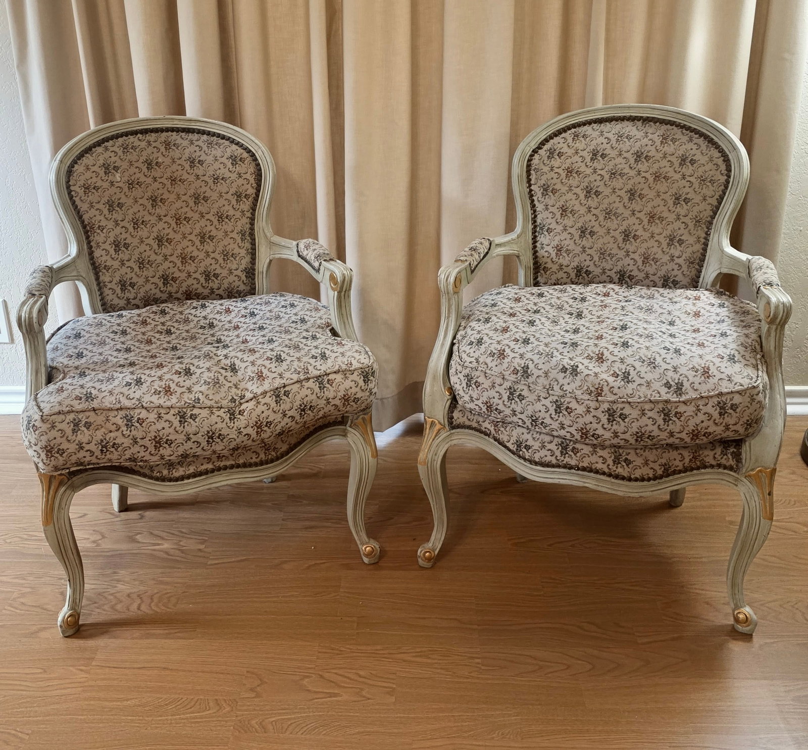 Pair of Antique French-style Upholstered Fauteuils: Antique French-style upholstered fauteuils with a painted and gilded finish, likely dating from the 19th to early 20th century. They feature typical Louis XV style characteristics, including curved