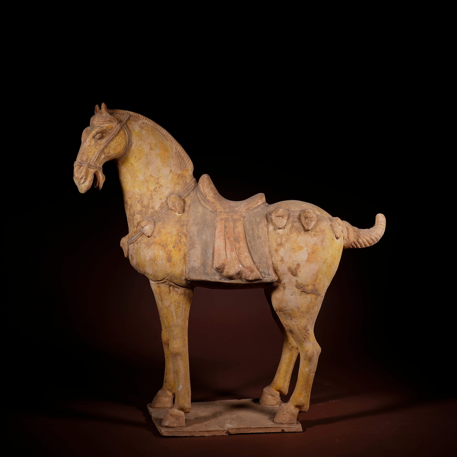 A PAINTED POTTERY STANDING HORSE FIGURINE: A PAINTED POTTERY STANDING HORSE FIGURINE Length: 44 cm (17.3 in.), Height: 48 cm (18.9 in.). All measurements are approximate.