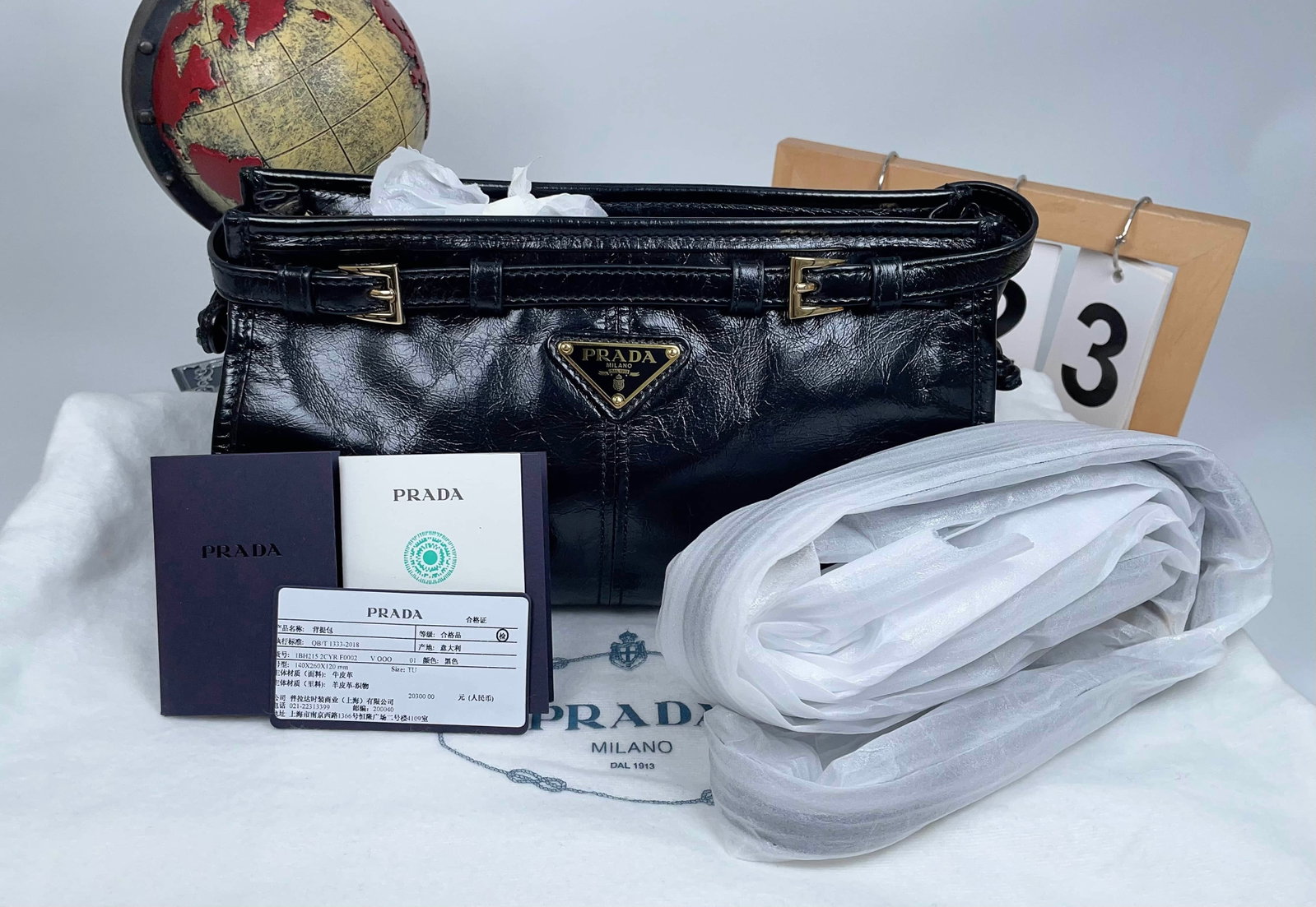 PRADA BONNIE BLACK WAXED-LEATHER SHOULDER BAG: PRADA BONNIE BLACK WAXED-LEATHER SHOULDER BAG Prada Bonnie black waxed leather shoulder bag, measuring 26 × 14 × 12 cm, crafted from soft waxed leather with a vintage sheen, featuring the iconic tri