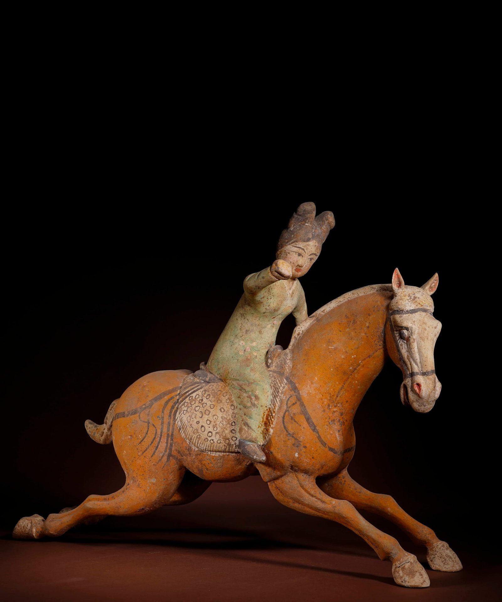 A PAINTED POTTERY 'FEMALE POLO-PLAYER' FIGURINE: A PAINTED POTTERY 'FEMALE POLO-PLAYER' FIGURINE Length: 41.5 cm (16.3 in.), Height: 32.5 cm (12.8 in.). All measurements are approximate.
