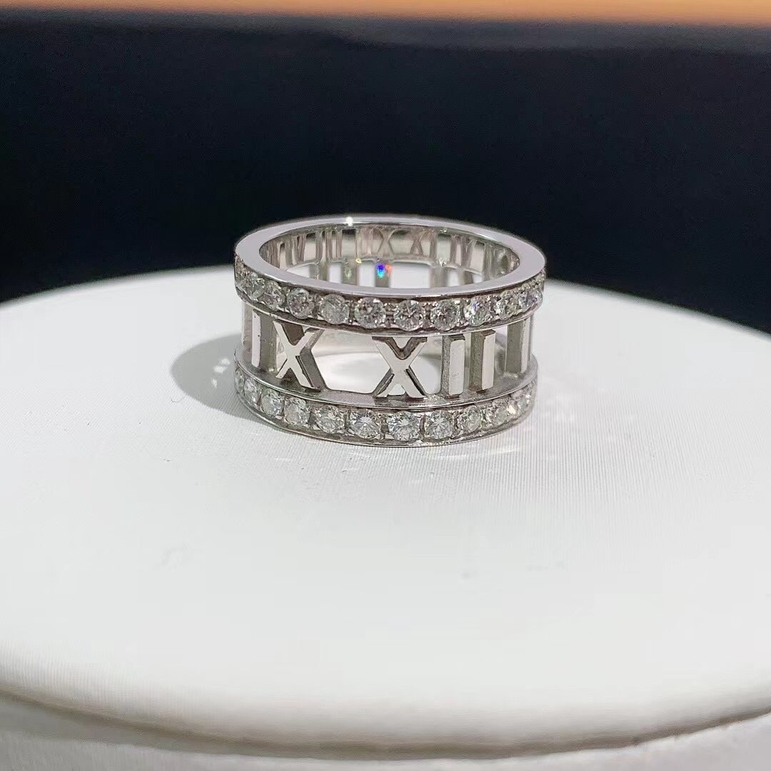 Tiffany & Co. Atlas Collection Open Roman Numeral Ring Size 49 Diamonds: Brand: Tiffany & Co.Collection: AtlasMaterial: 18k White GoldGemstones: Features approximately 30 round brilliant-cut diamondsDesign: A wide openwork band featuring Roman numeral motifs bordered by tw