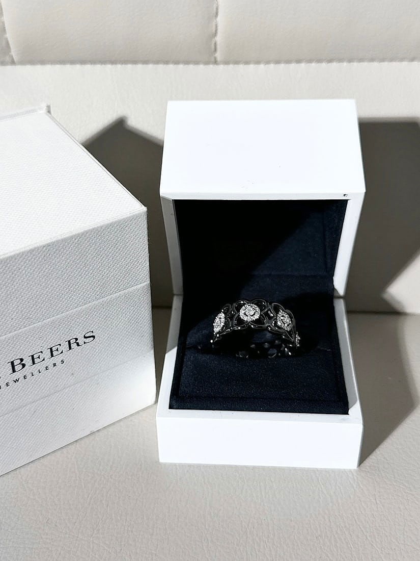 De Beers Black Ceramic 18k White Gold Diamond Lotus Ring Size 57: De Beers Enchanted Lotus Moonlight Band. This striking piece features a graphic interpretation of the lotus flower, a symbol of purity and eternity, using a bold contrast of materials.Key Design Eleme