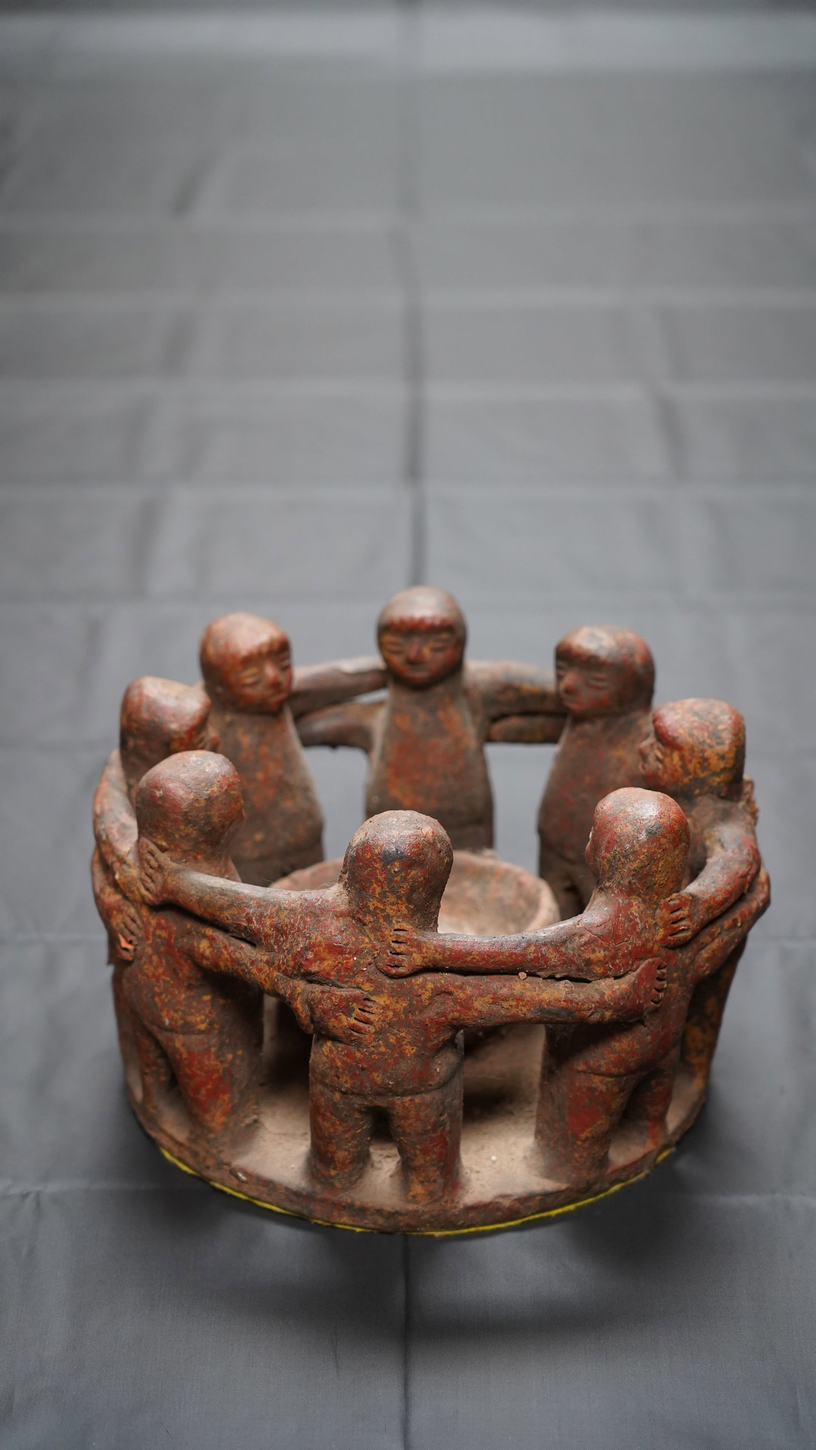 Vintage Mexican Folk Art Circle of Friends Terracotta Candle Holder Sculpture: Handcrafted vintage Mexican folk art terracotta “Circle of Friends” candle holder sculpture depicting eight figures standing arm-in-arm around a central candle well. Finished in earthy red and