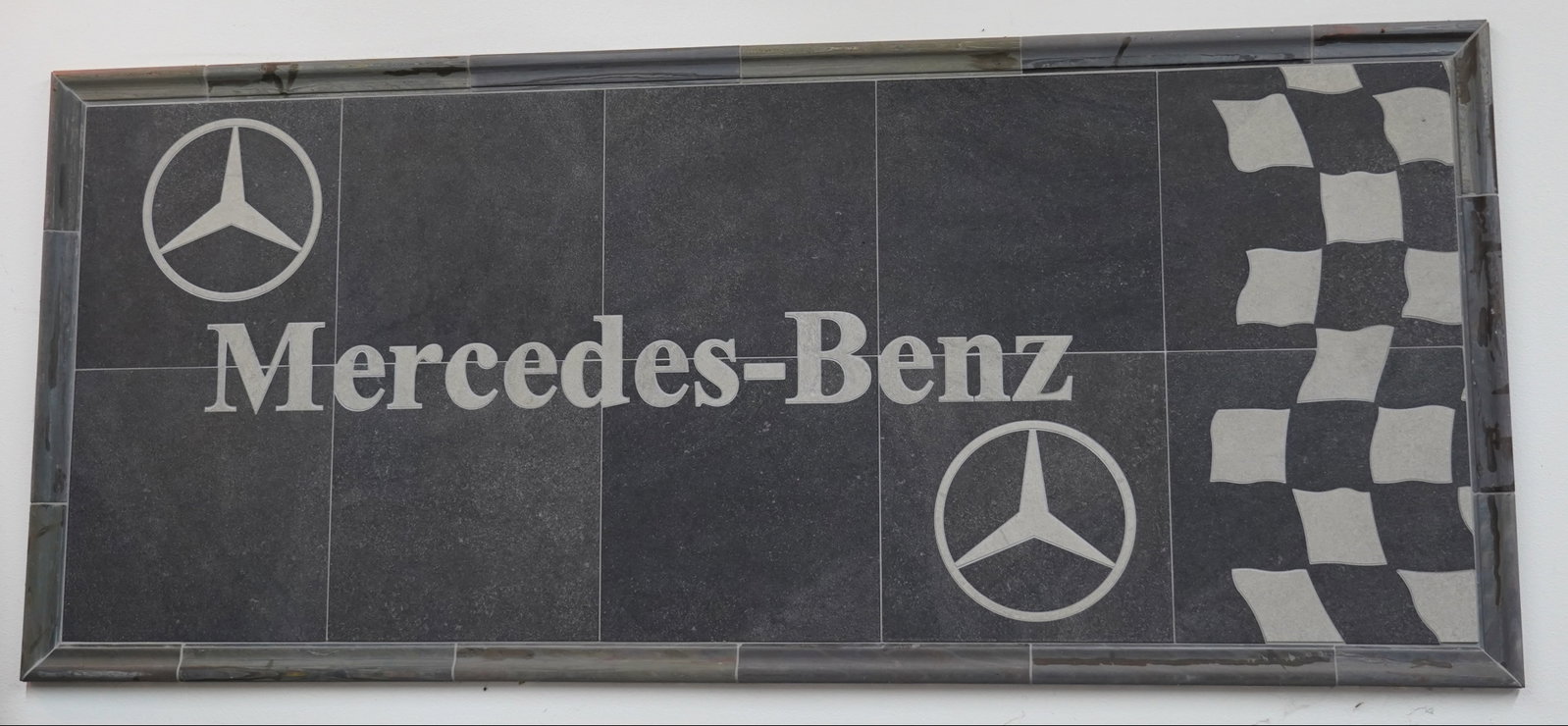 Mercedes Benz Tile Mosaic Wall Art Racing Checkered Large Framed Display: Large Mercedes Benz themed tile mosaic wall art featuring brand name and triple star logos with racing checkered design. Constructed from multiple tiles forming a bold automotive display. Framed and r