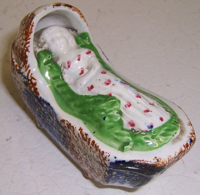 19th century Staffordshire figurine: 19th century Staffordshire figurine of child in cradle. 3 1/2" long.