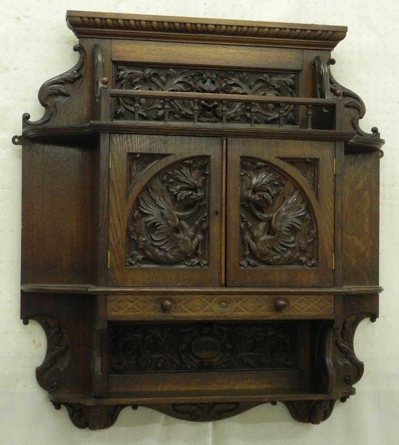 Heavily carved oak wall cabinet dated 1905: Heavily carved oak wall cabinet dated 1905, with griffon panels. 37" wide x 41" tall x 8" deep.
