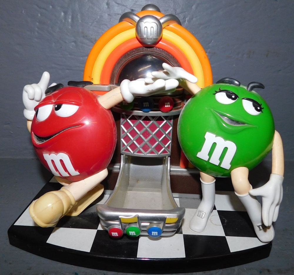 M&M Dispenser: M&M Dispenser. 9 1/2" x 8" H ALL DESCRIPTIONS AND ANY CONDITION STATEMENT GIVEN BY LANGSTON AUCTION GALLERY ARE STRICTLY OPINIONS AND LANGSTON'S SHALL HAVE NO RESPONSIBILITY FOR ERRORS OR OMISSIONS. T