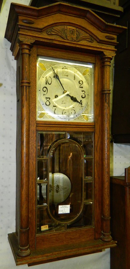 8 day German oak wall clock w/13" x 30 1/2".: Eight day German oak wall clock with columns and beveled glass panels. One piece of the molding is missing.13" x 30 1/2"