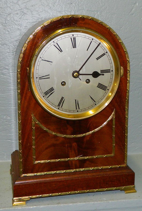 German mahogany 8 day bracket shelf clock.: German mahogany eight day bracket shelf clock with Roman numerals and brass attachments and feet. 10 1/4" x 15".