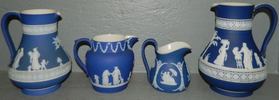 (4) Wedgwood pitchers in various sizes.: (4) Wedgwood pitchers in various sizes. One has a small chip in the lip. One has a staple in the handle. Range 4" - 8".