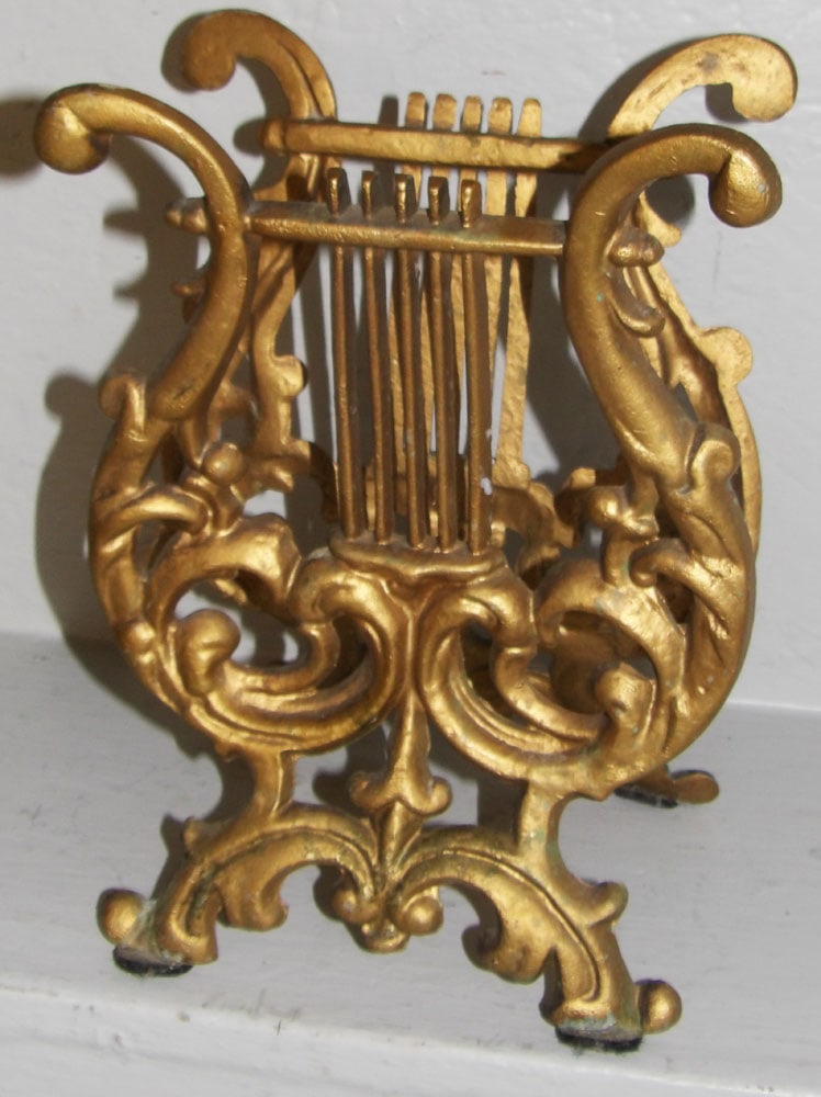 Ornate Gilded Metal Lyre Form Music Book Holder: Ornate Gilded Metal Lyre Form Music Book Holder . 11" H 8" W 6" D ALL DESCRIPTIONS AND ANY CONDITION STATEMENT GIVEN BY LANGSTON AUCTION GALLERY ARE STRICTLY OPINIONS AND LANGSTON'S SHALL HAVE NO RESP