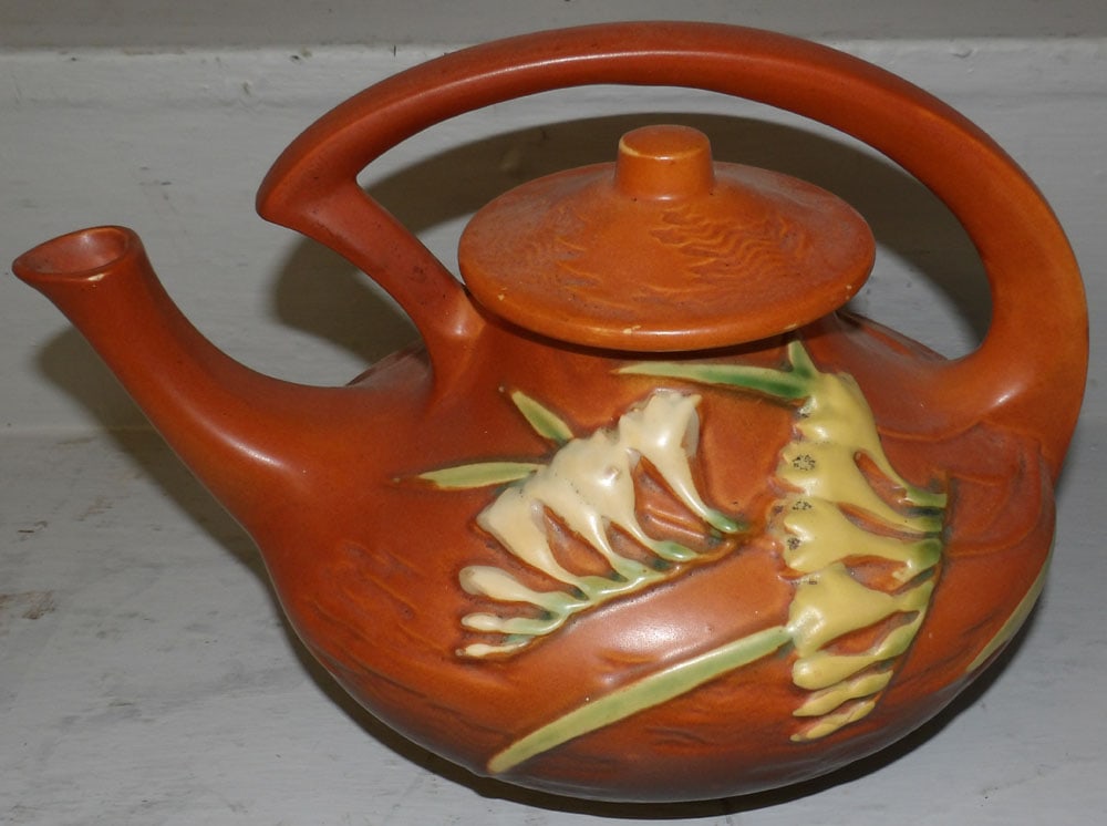 Roseville freesia pottery teapot: Roseville freesia pottery teapot . 7 1/2" H 11" W 7 1/2" D ALL DESCRIPTIONS AND ANY CONDITION STATEMENT GIVEN BY LANGSTON AUCTION GALLERY ARE STRICTLY OPINIONS AND LANGSTON'S SHALL HAVE NO RESPONSIBIL