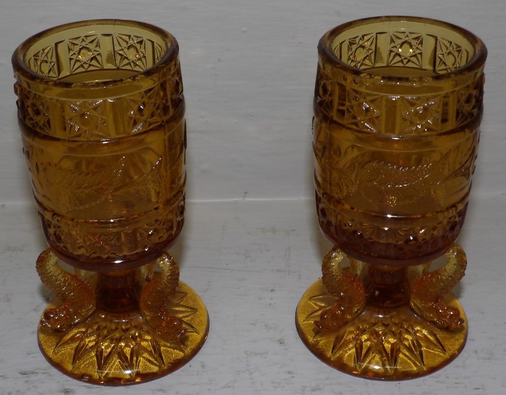 Pair of Amber Glass Toothpick Holders with Dolphin Bases: Pair of Amber Glass Toothpick Holders with Dolphin Bases. 4 1/4" H 2" Dia. ALL DESCRIPTIONS AND ANY CONDITION STATEMENT GIVEN BY LANGSTON AUCTION GALLERY ARE STRICTLY OPINIONS AND LANGSTON'S SHALL HAV