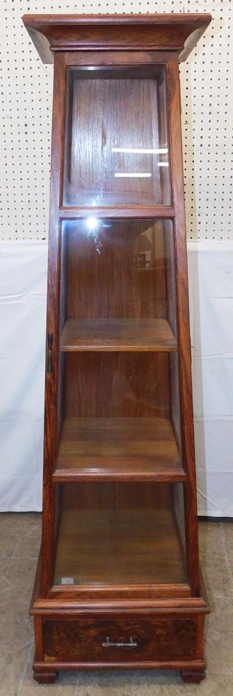 Teak Wood One Door One Drawer Obelisk Form Display Cabinet: Teak Wood One Door One Drawer Obelisk Form Display Cabinet. 62 3/4" H 18" W 18" D ALL DESCRIPTIONS AND ANY CONDITION STATEMENT GIVEN BY LANGSTON AUCTION GALLERY ARE STRICTLY OPINIONS AND LANGSTON'S