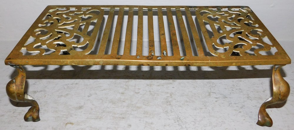 Antique Brass Trivet: Antique Brass Trivet. 5 3/4" H 18 1/2" W 9" D ALL DESCRIPTIONS AND ANY CONDITION STATEMENT GIVEN BY LANGSTON AUCTION GALLERY ARE STRICTLY OPINIONS AND LANGSTON'S SHALL HAVE NO RESPONSIBILITY FOR