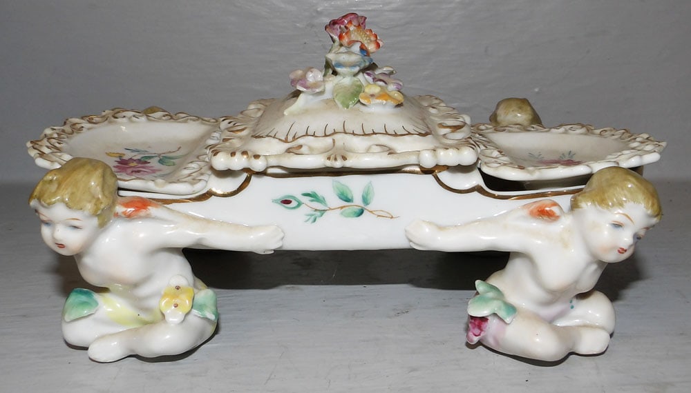 Painted Porcelain Figural Cupid Dresser Box: Painted Porcelain Figural Cupid Dresser Box . 4" H 8 1/4" W 5 1/2" D "ALL DESCRIPTIONS AND ANY CONDITION STATEMENT GIVEN BY LANGSTON AUCTION GALLERY ARE STRICTLY OPINIONS AND LANGSTON'S SHALL HAVE NO