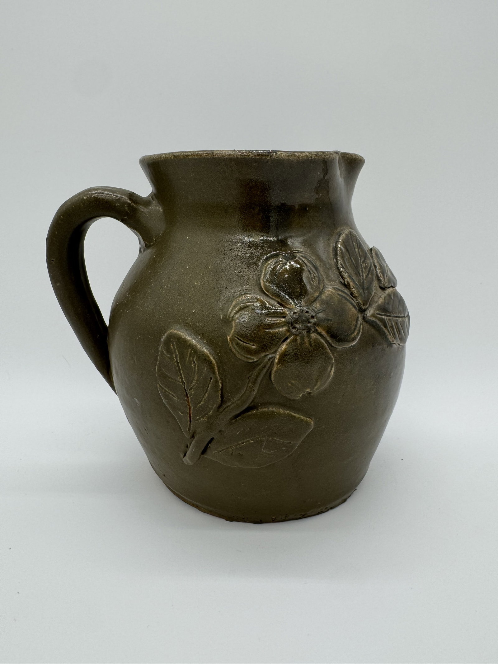 Arie Meaders Decorated Pitcher: A beautiful decorated pitcher by Arie Meaders, with the form turned by Cheever Meaders. This example features an applied dogwood flower and is finished in a rich green glaze. Signed.