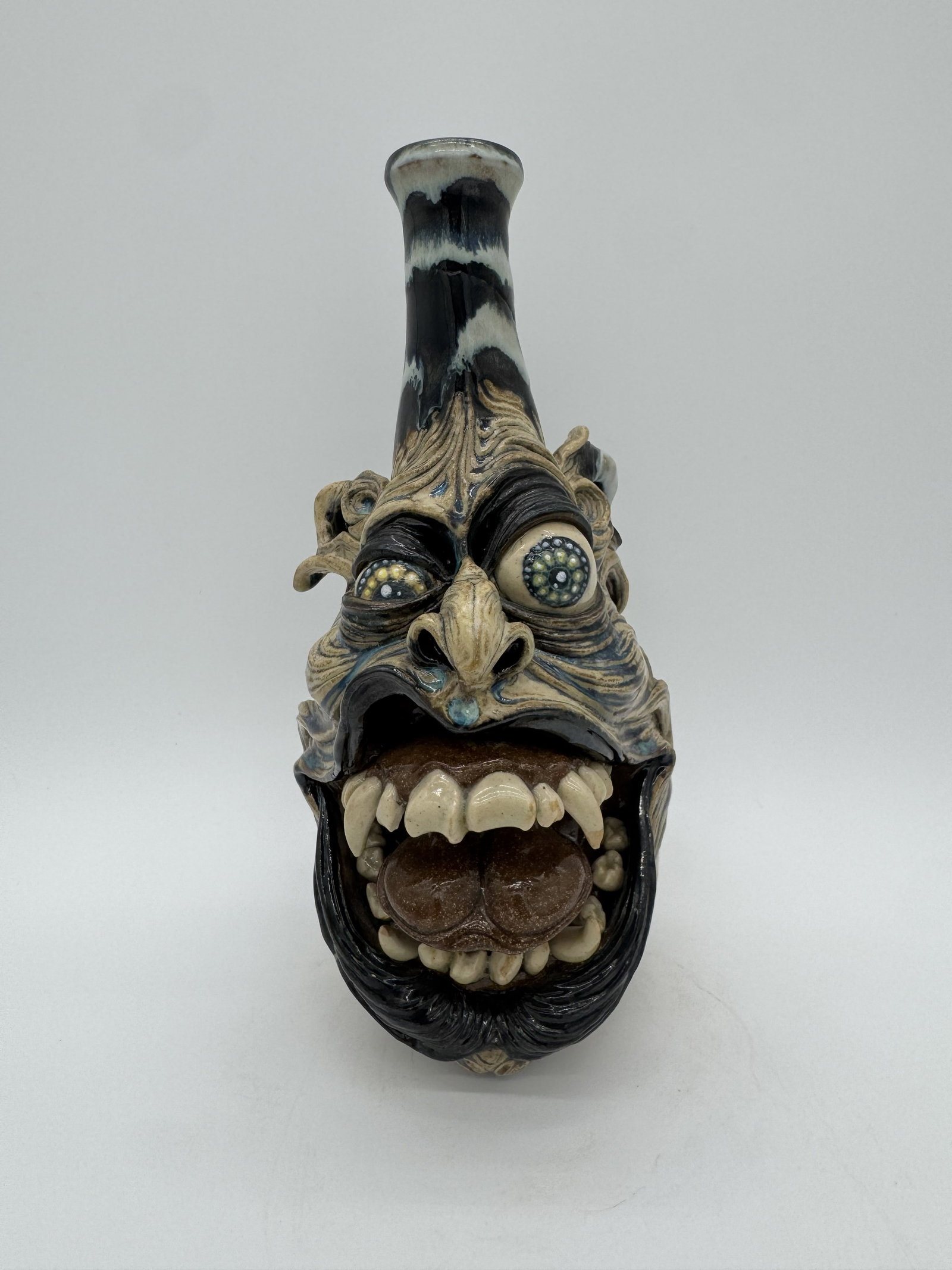 Ron Dahline Face Jug: A face jug by Ron Dahline, featuring a bold open mouth that gives the piece strong character and presence. This example displays detailed features and vibrant colors. Signed.