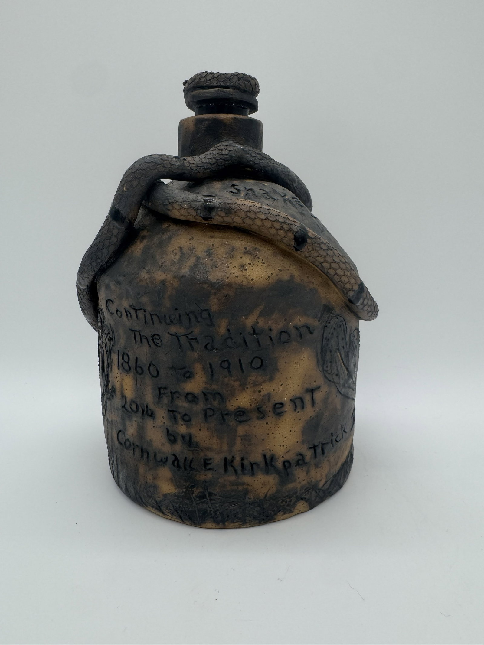 Cornwall E. Kirkpatrick IV Snake Juice Jug: A “Snake Juice” jug by Cornwall E. Kirkpatrick IV, featuring multiple snake elements across the surface, including a snake-form stopper at the top. The piece carries an inscription on the