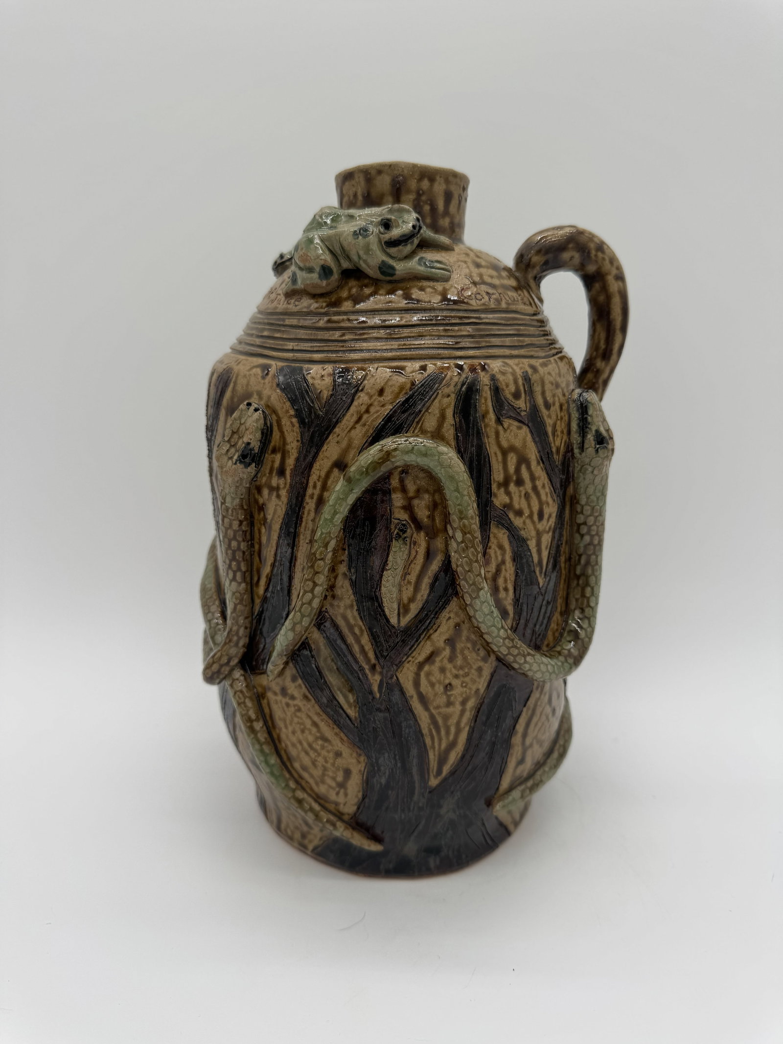 Cornwall E. Kirkpatrick IV Snake Juice Jug: A “Snake Juice” jug by Cornwall E. Kirkpatrick IV, featuring multiple snake elements across the surface, including a snake-form stopper at the top. This example also includes a frog and