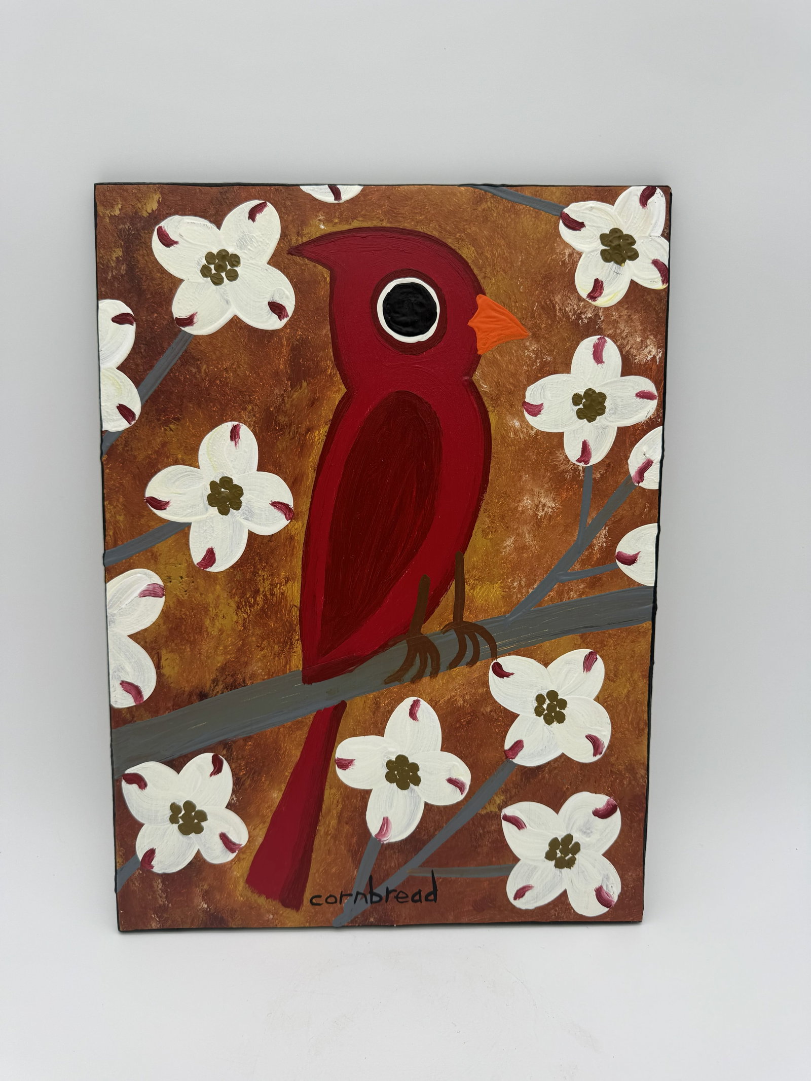 John "Cornbread" Anderson Red Cardinal Painting: A painting by John “Cornbread” Anderson, depicting a red cardinal rendered in vibrant colors. This example is executed on a plywood board. Signed.