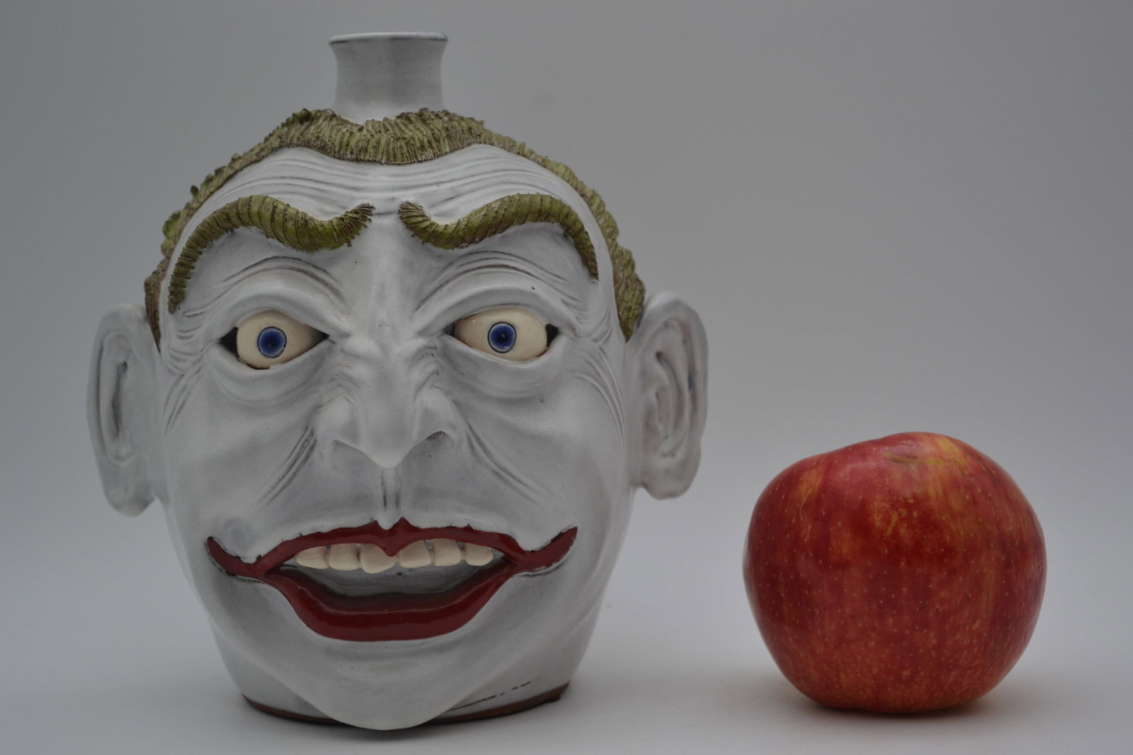 Daniel Boone #1 Joker Face Jug: A No. 1 Joker face jug by Daniel Boone. This highly detailed example is full of character and visual impact, showcasing outstanding craftsmanship and creativity. Bold red lips, bright blue eyes, a whi