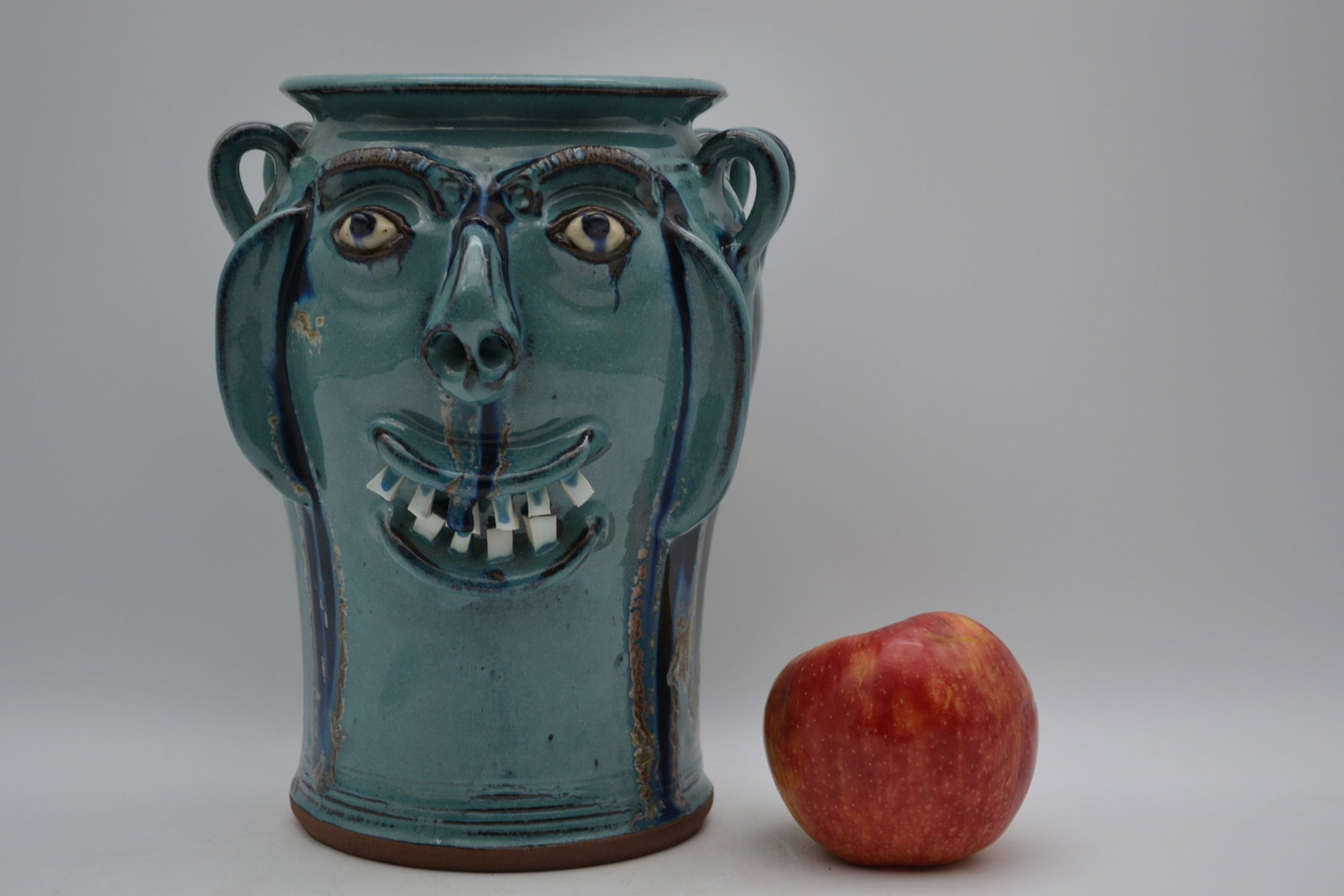 A.V. Smith Face Vase: A beautiful face vase by A.V. Smith. Gracefully formed with an elegant, flared rim, this striking face vase is finished in a beautiful light blue glaze that gives the piece a soft, refined appearance.