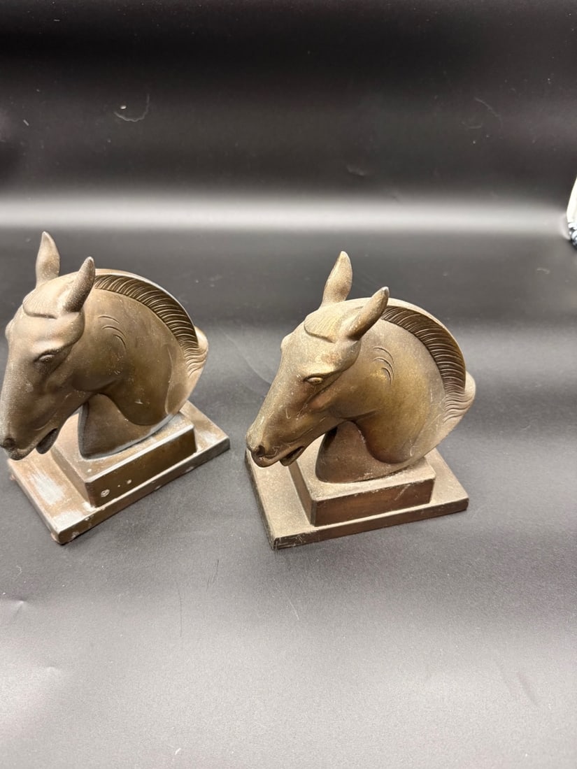 Antique Frankart Horse Head Bookends (Pair): A pair of vintage Art Deco style horse head bookends are crafted from heavy metal with a bronze patina over metal and feature a stylized streamlined design. Mid Century Era. Both missing felt plate
