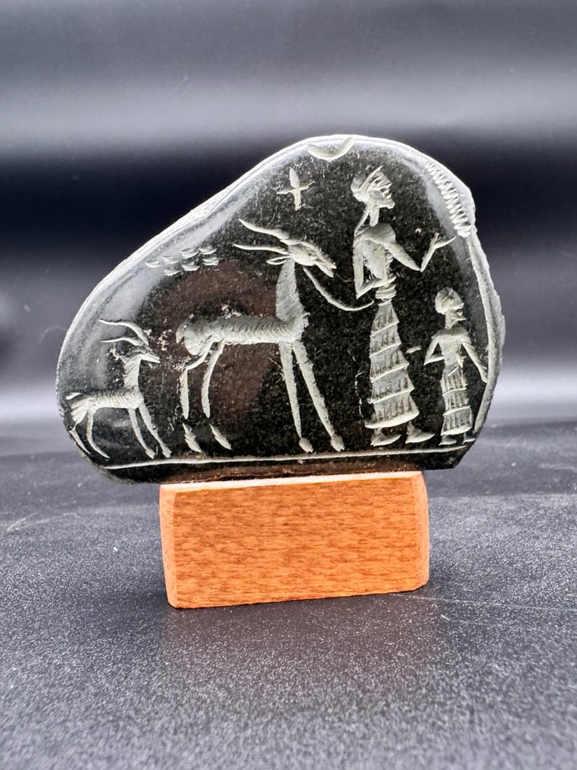 Carving Sculpture On Polished stone Standing on Wooden Base: Lovely decorative stone carving. This carving could possibly be representing ancient Near Eastern or Egyptian artistry featuring engraved figures of animals and people. The scene depicts a person