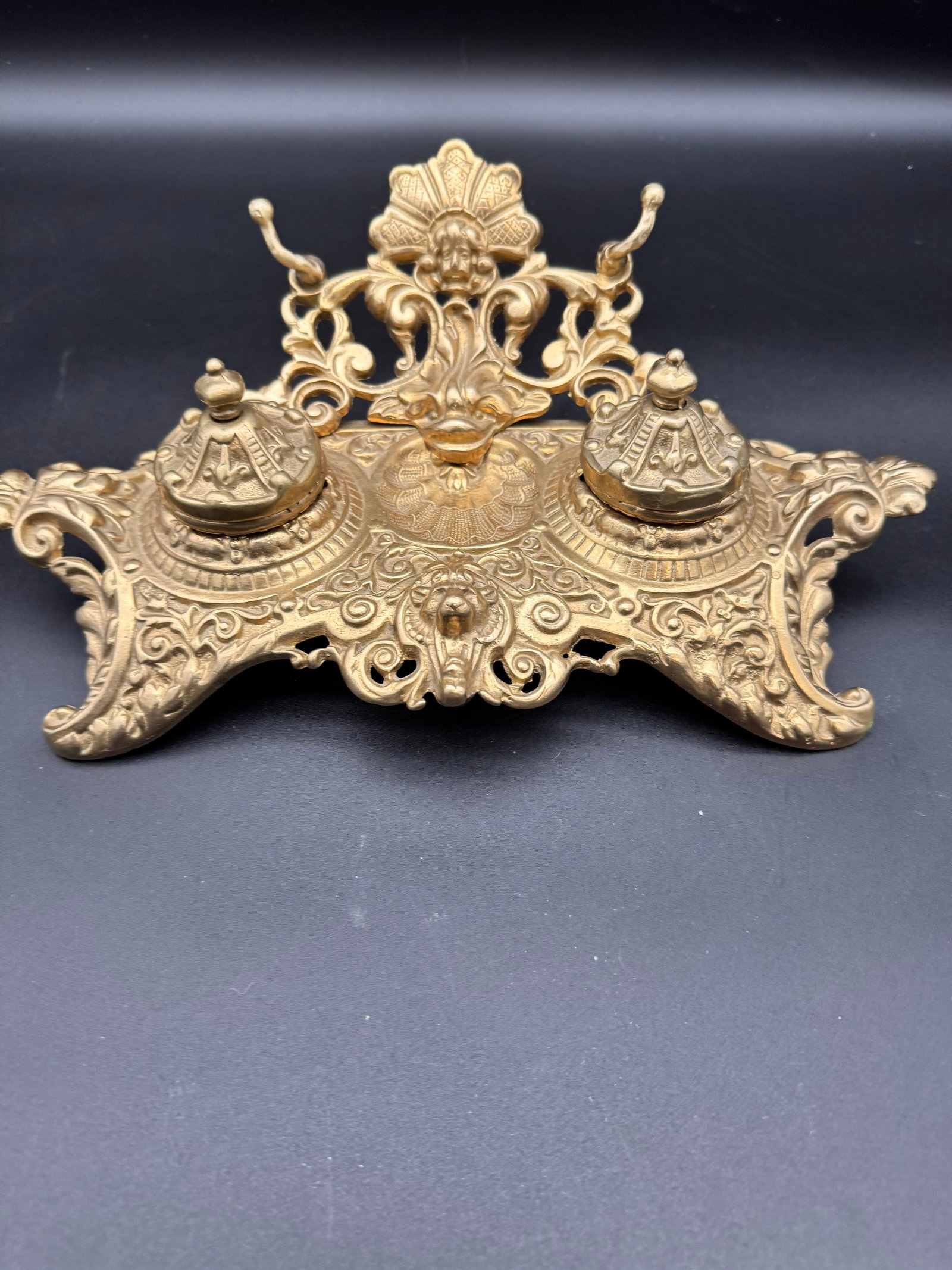 Vintage Ornate Brass Double Inkwell with Lion Cherub: Vintage double inkwell featuring a Baroque or Art Nouveau style with figural details such as cherubs and lions. This beautiful ink holder is a unique statement piece offering a rich, luxurious office 