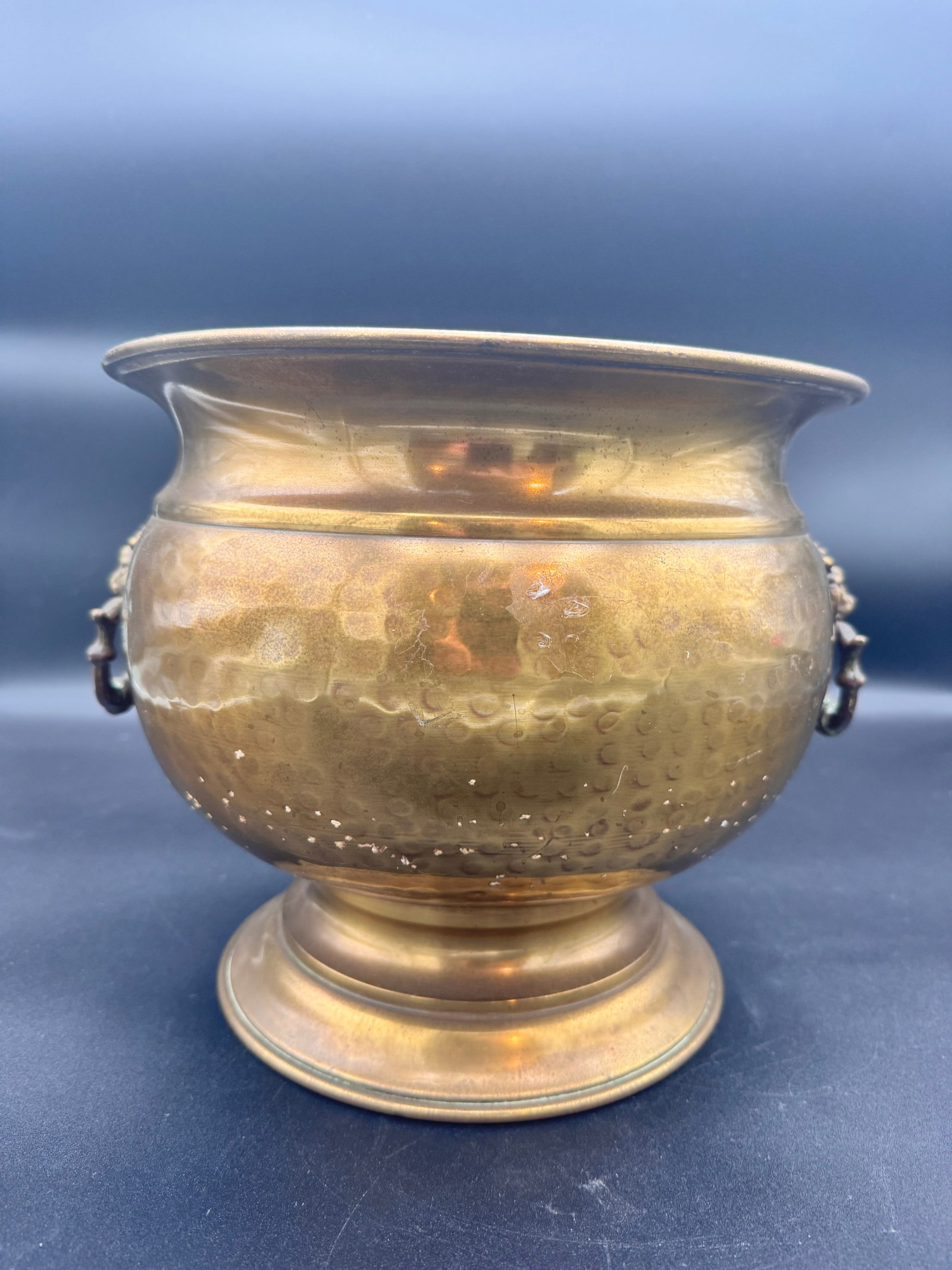 Vintage Hammered Antique Brass Lion Head Parlor Spittoon Planter: Features hammered indentations across the vessel and ornamental lion head mounts with rings. Commonly used as a decorative plater, cachepot or vase for plants. Constructed from brass and features a ro