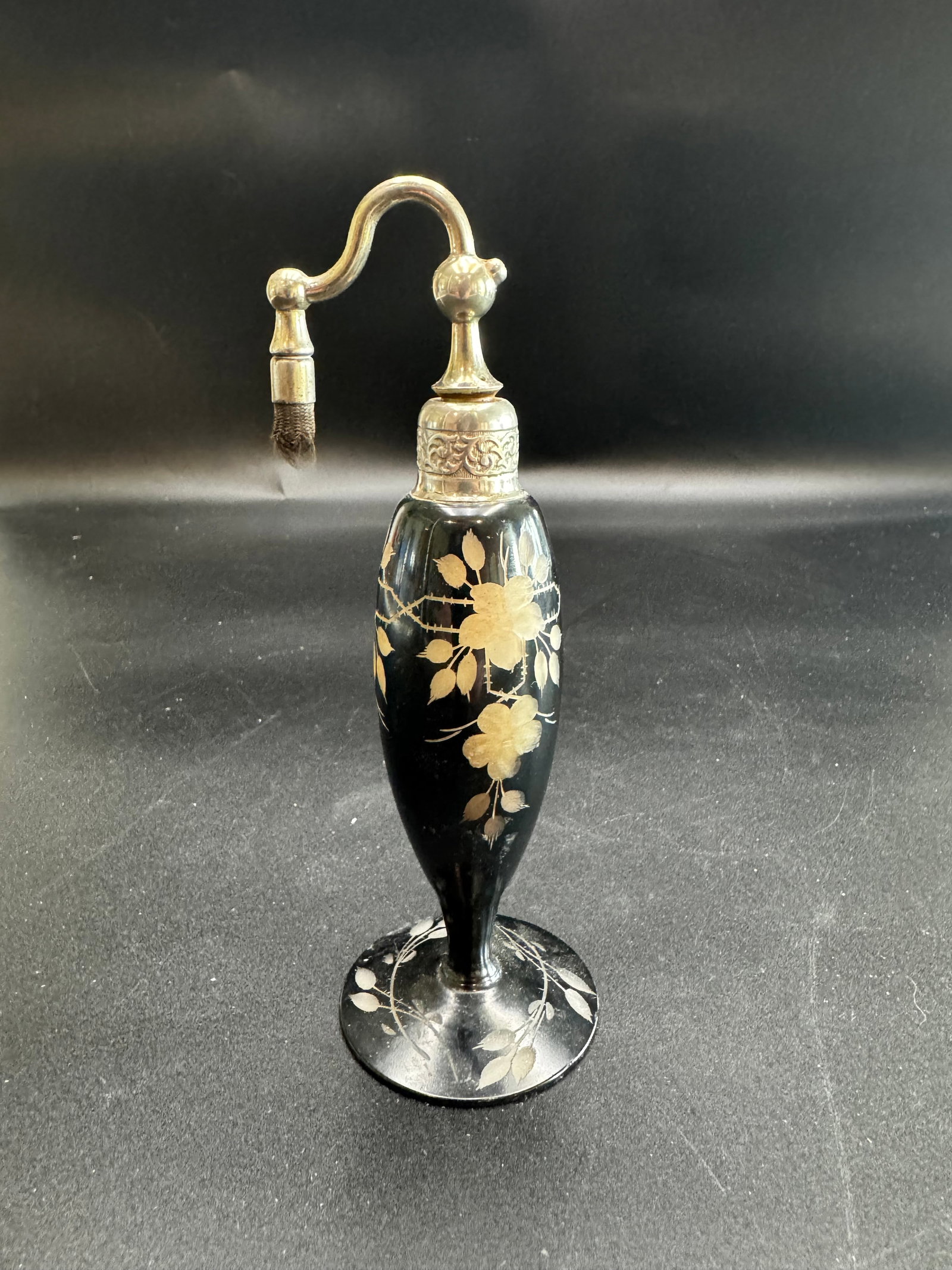 Vintage Art Deco Perfume Atomizer: This item was likely produced by the DeVilbiss Company, known for operating from the early 1900s through the mid-1950s. It is designed with a black glass base featuring gold floral motifs and an