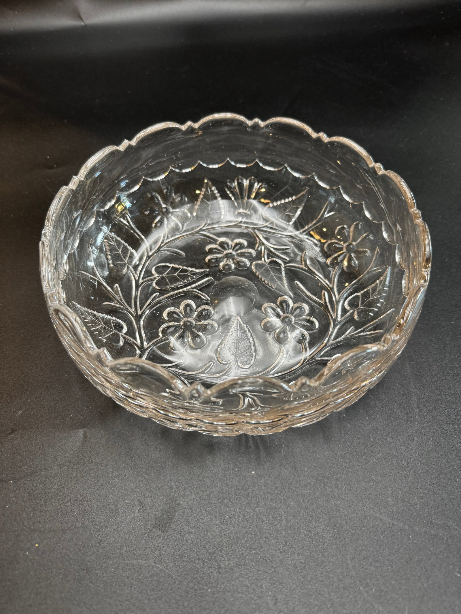 Vintage Clear Glass Daisy Bowl: The interior features detailed wheel-cut daisies, long sweeping stems, and textured leaves arranged symmetrically around a central circular base. The upper perimeter is styled with a smooth, sweeping